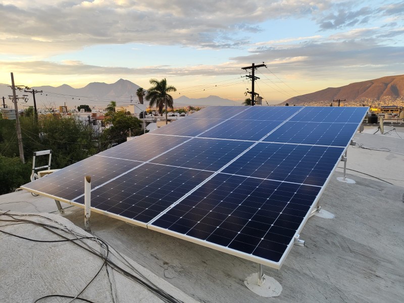 Paneles solares sobre una losa en Monterrey al atardecer, con la sierra al fondo